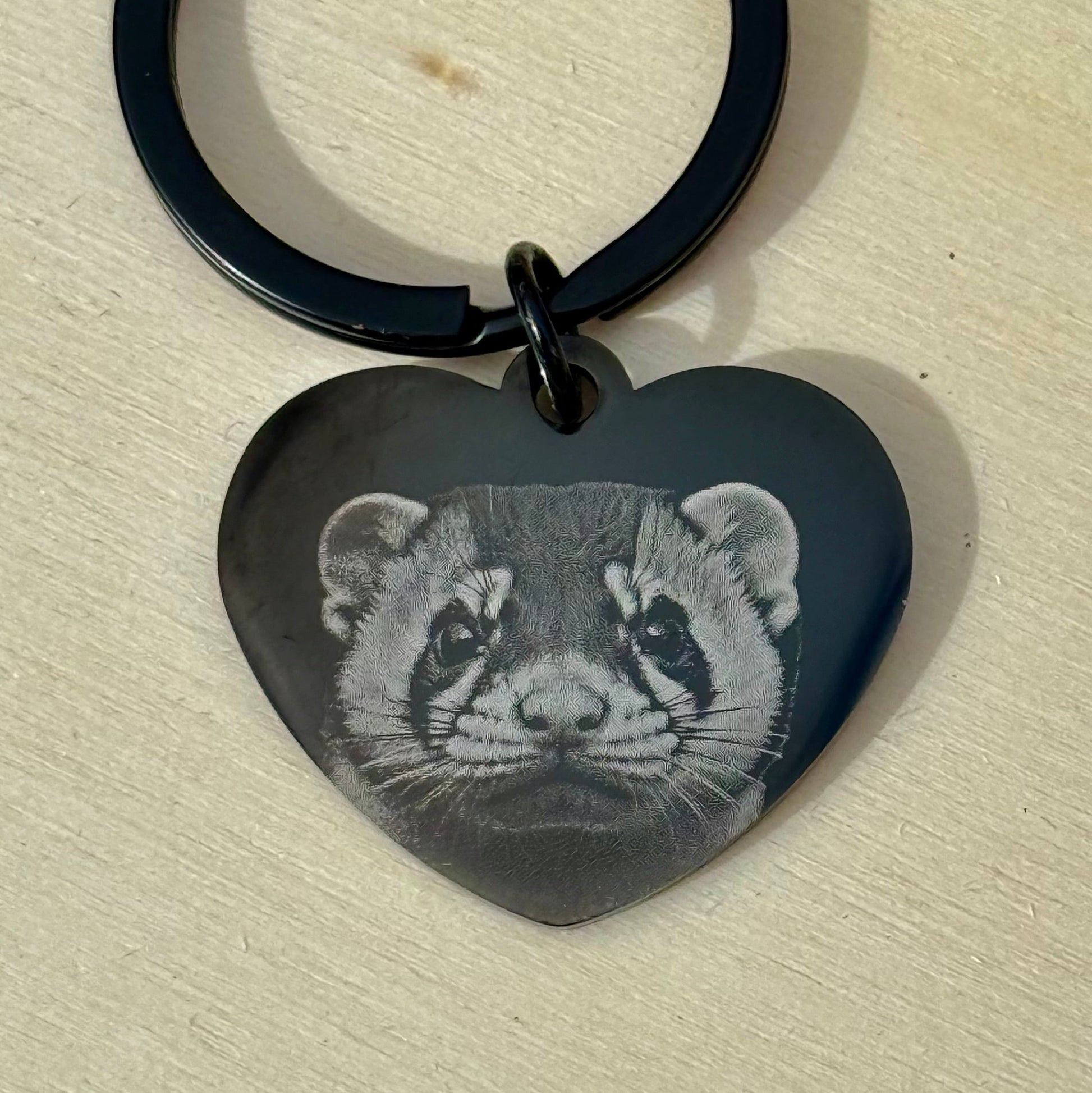Heart-shaped keychain with a black and white animal design on a beige surface